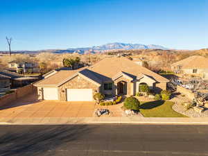 View of front of house with stone siding, a garage, concrete driveway, a residential view, and a mountain view