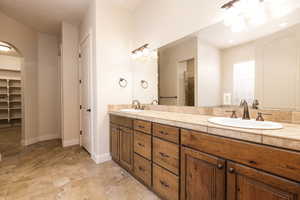Full bath featuring double vanity, a walk in closet, and a stall shower