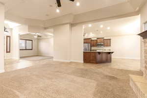 Unfurnished living room featuring ceiling fan, recessed lighting, light colored carpet, and light tile patterned flooring