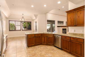 Kitchen featuring a peninsula, pendant lighting, light stone countertops, dishwasher, and recessed lighting