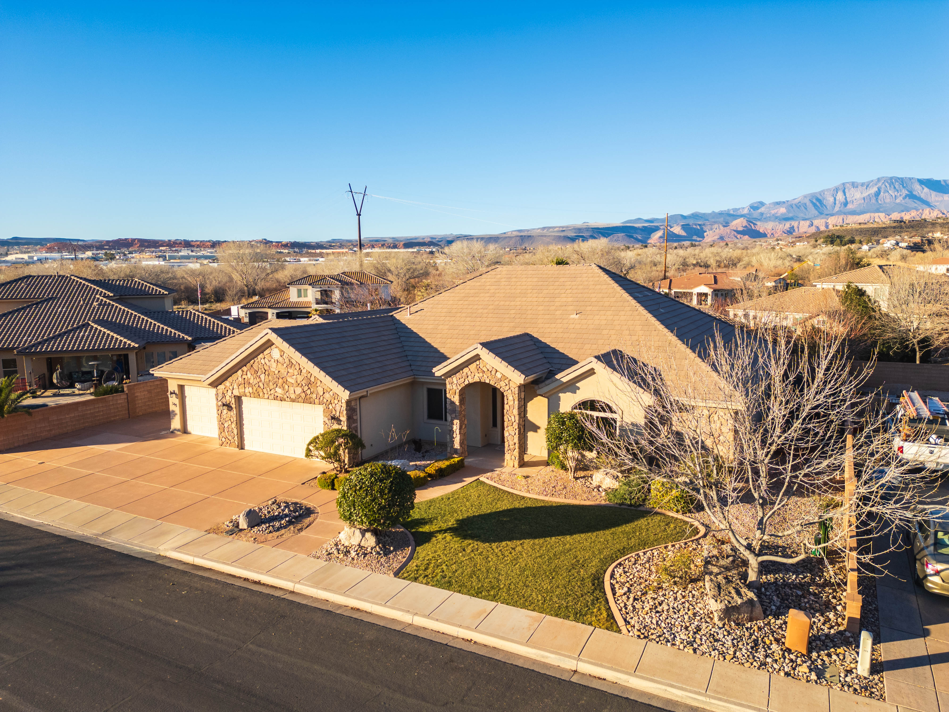 Ranch-style home with stone siding, concrete driveway, an attached garage, and a front lawn