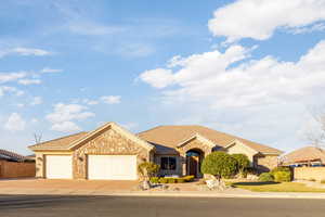 Single story home featuring stone siding, an attached garage, driveway, and a tile roof