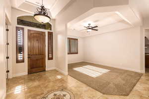 Foyer entrance with a tray ceiling and a ceiling fan