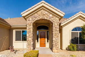 Doorway to property featuring stone siding, stucco siding, and a tiled roof