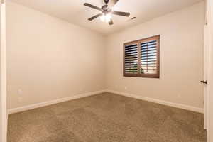 Carpeted spare room featuring baseboards and ceiling fan
