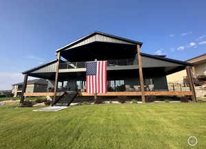 Back of property with a lawn, covered porch, and stairs