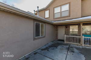 View of side of property with stucco siding, a patio, and brick siding
