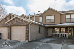 View of front of property featuring stucco siding, driveway, and brick siding