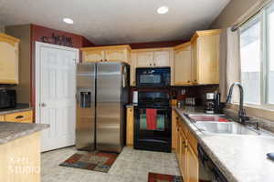 Kitchen featuring black appliances, light brown cabinets, and recessed lighting