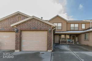 Traditional-style home featuring brick siding, concrete driveway, stucco siding, covered porch, and a garage