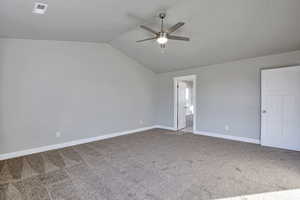 Unfurnished bedroom featuring carpet floors, lofted ceiling, a ceiling fan, and connected bathroom