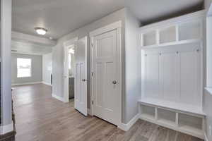 Mudroom featuring light wood-style floors and baseboards