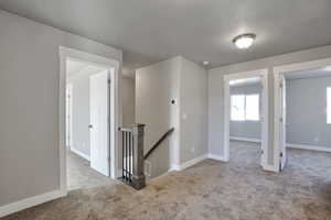 Empty room with light carpet and a textured ceiling