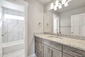 Bathroom with vanity, light marble finish floors, and shower / washtub combination