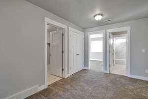 Unfurnished bedroom with ensuite bathroom, a closet, and light colored carpet