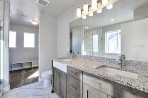 Full bathroom with a marble finish shower, double vanity, and light marble finish flooring
