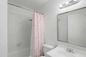Full bath featuring a textured wall, shower / bath combo with shower curtain, and vanity