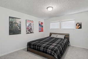 Carpeted bedroom featuring a textured ceiling and baseboards