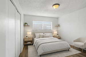 Bedroom featuring dark wood-type flooring, a textured ceiling, and a closet