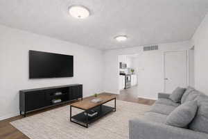Living area featuring dark wood-style flooring and a textured ceiling
