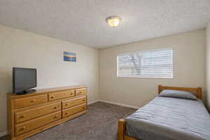 Bedroom with dark carpet and a textured ceiling