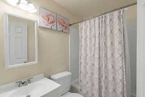 Full bathroom with vanity, shower / bath combo, and a textured wall