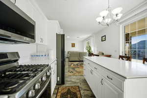 Kitchen with stainless steel appliances, white cabinetry, open floor plan, and light countertops