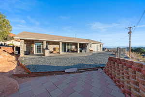 Rear view of property with a patio, roof with shingles, and brick siding
