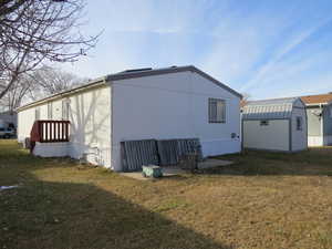 View of side of home featuring a yard and a storage unit