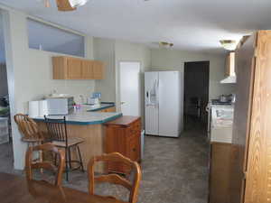 Kitchen with white appliances, a kitchen breakfast bar, a peninsula, and light countertops