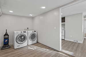 Laundry area featuring wood finished floors, separate washer and dryer, and recessed lighting