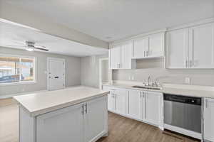 Kitchen with white cabinets, light wood finished floors, a textured ceiling, stainless steel dishwasher, and ceiling fan