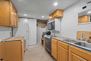 Kitchen featuring freestanding refrigerator, concrete flooring, electric range oven, recessed lighting, and black microwave