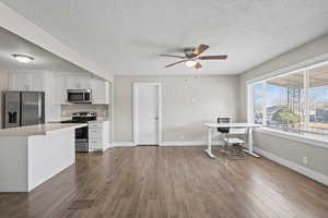 Kitchen featuring appliances with stainless steel finishes, white cabinets, dark wood-type flooring, a ceiling fan, and a textured ceiling