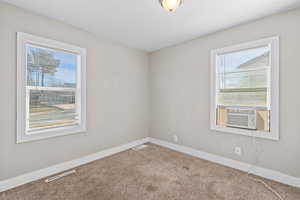 Carpeted empty room with baseboards and cooling unit