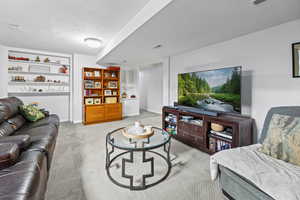 Living area with a textured ceiling and light colored carpet