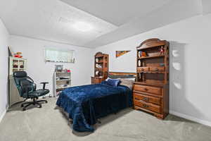 Bedroom featuring a textured ceiling and light colored carpet