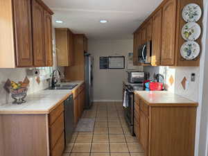 Kitchen featuring tile countertops, backsplash, brown cabinets, and recessed lighting