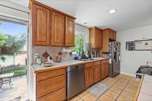 Kitchen with wood finish cabinets, stainless steel appliances, tasteful backsplash, light tile patterned floors, and recessed lighting