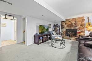 Living room with a stone fireplace, light colored carpet, and a textured ceiling