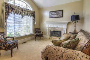 Living room with lofted ceiling, a fireplace, and carpet flooring