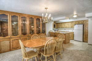 Dining space featuring a chandelier, a textured ceiling, light tile patterned floors, and light carpet