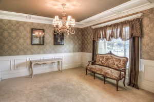 Sitting room with a decorative wall, wallpapered walls, wainscoting, ornamental molding, and carpet flooring