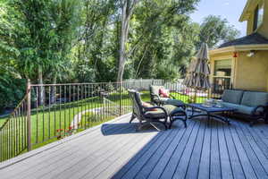 Deck with an outdoor living space and view of wooded area