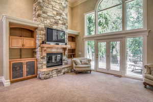 Living room featuring a high ceiling, a fireplace, crown molding, and light colored carpet