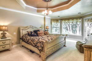 Bedroom with access to outside, crown molding, carpet floors, a raised ceiling, and a chandelier