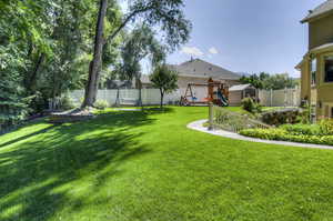 Fenced backyard featuring a playground and a storage shed