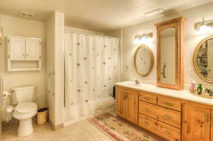 Bathroom with vanity, shower / tub combo with curtain, light tile patterned floors, and a textured ceiling