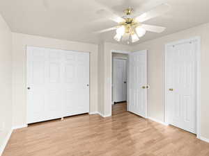 Unfurnished bedroom with light wood-style floors, a ceiling fan, and a closet