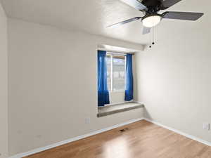 Empty room with light wood finished floors and a ceiling fan